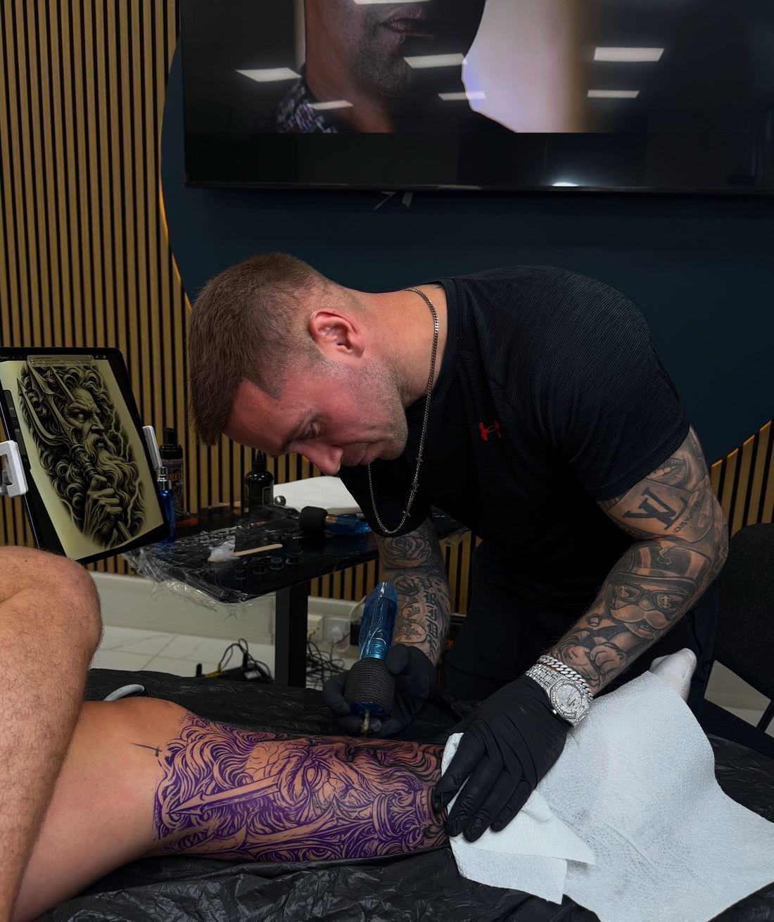Paul Denniston tattooing a client's leg